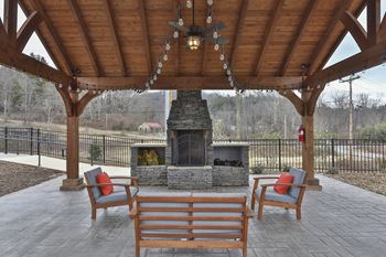 A wooden gazebo with a fireplace and chairs.